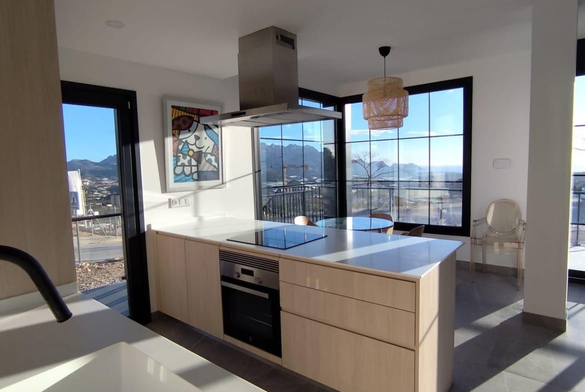 Kitchen with an island, oven and large windows in a Polop show home, Alicante