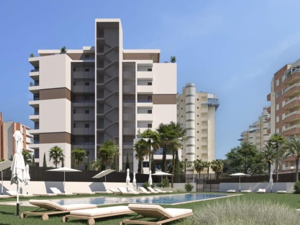 Communal swimming pool with sunloungers and lawns beside a modern apartment building in Guardamar del Segura, Alicante
