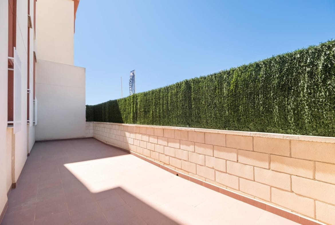 Tiled outdoor area beside a privacy hedge in Lomas de Cabo Roig, Alicante