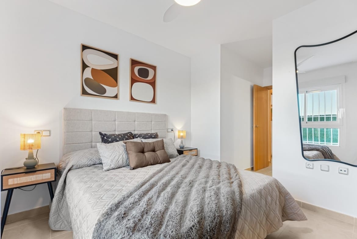 Double bedroom with wall mirror and framed artwork in Lomas de Cabo Roig, Alicante